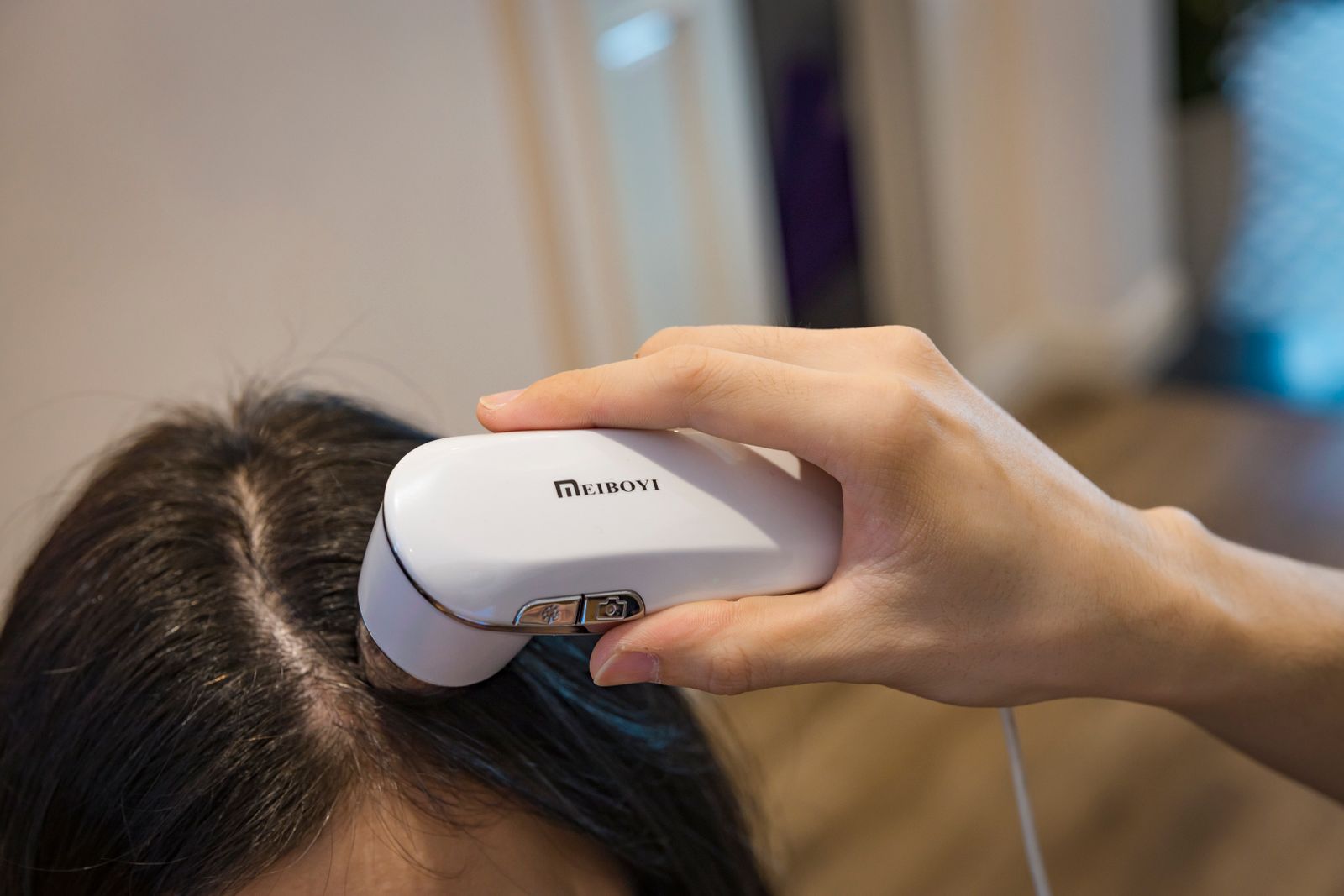 Close-up of a handheld scalp examination device being used along a hair parting
